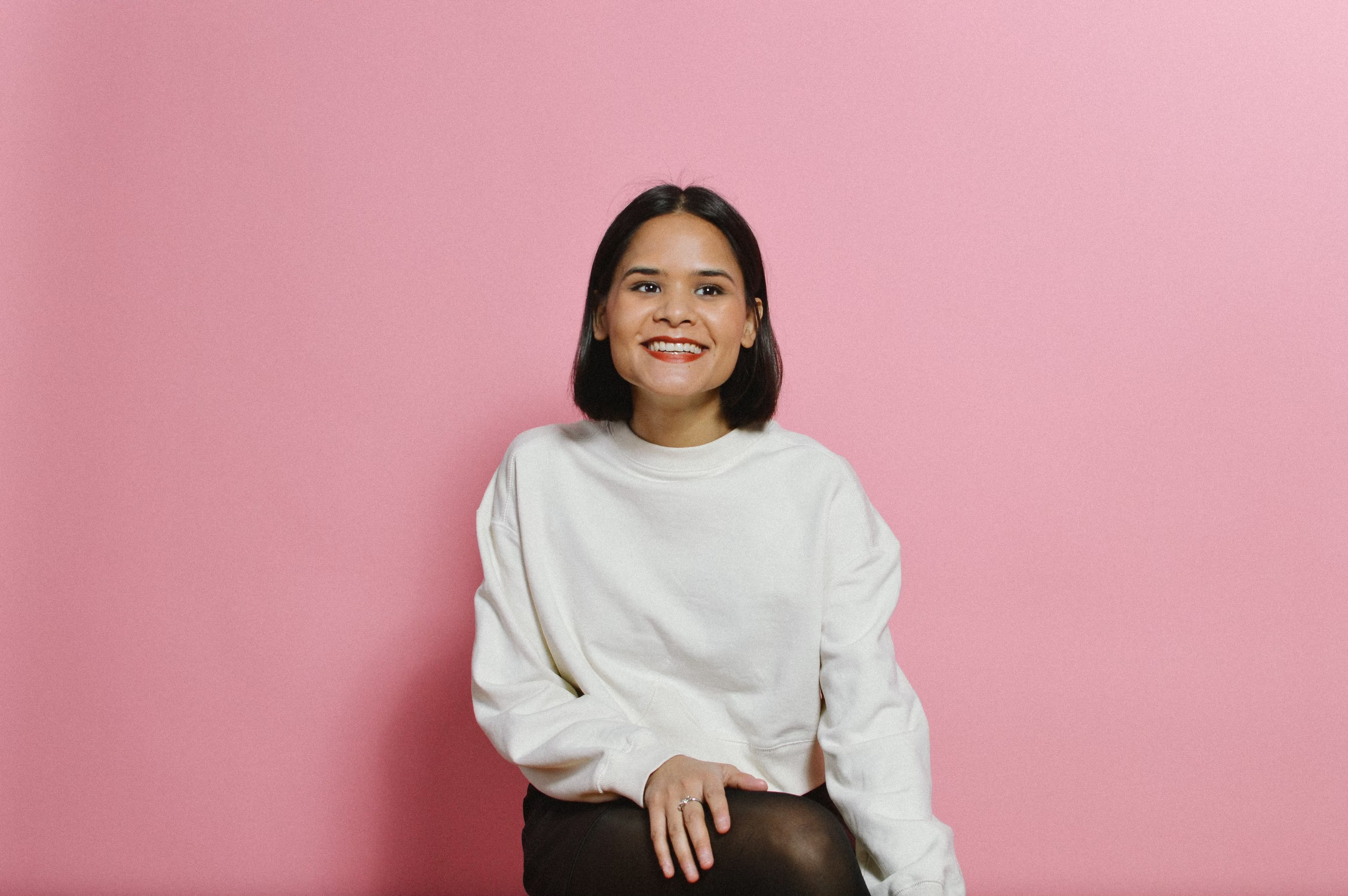 KC Shornima smiling in front of a pink background.